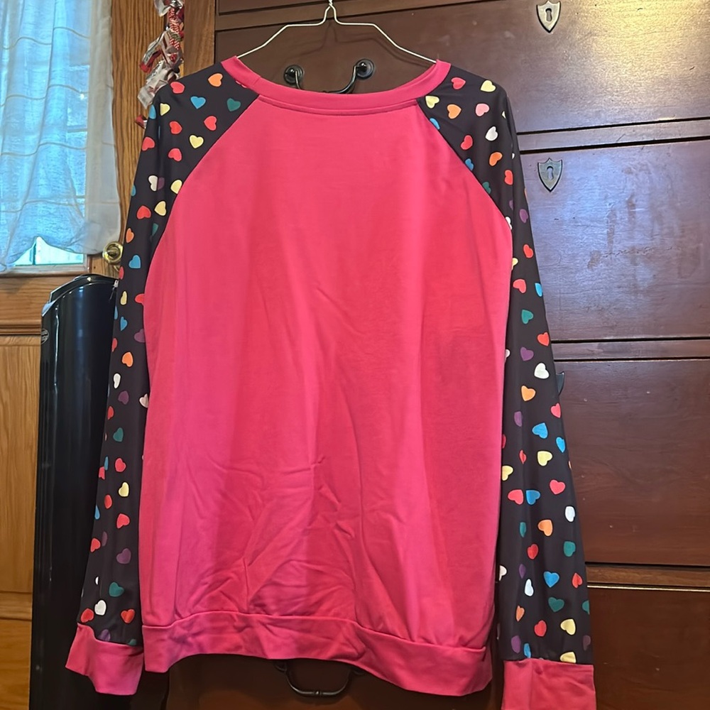 Cute Valentine’s Day sweater aligned with hearts down the sleeves, pink base